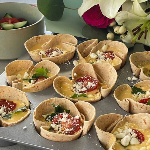 tortilla egg cups in a muffin tray with feta cheese sprinkled on top
