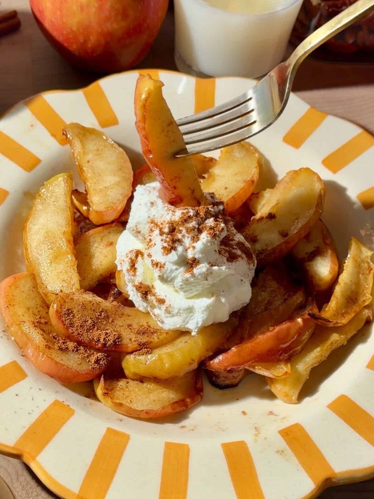 Air fryer apples with cinnamon and Greek yogurt on a yellow striped plate