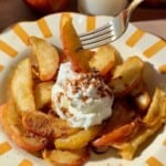 Air fryer apples with cinnamon and Greek yogurt on a yellow striped plate