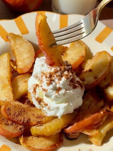 Air fryer apples with cinnamon and Greek yogurt on a yellow striped plate