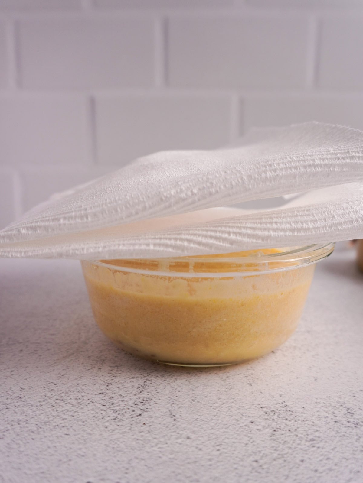 A glass bowl covered with kitchen paper ready to go into the microwave.