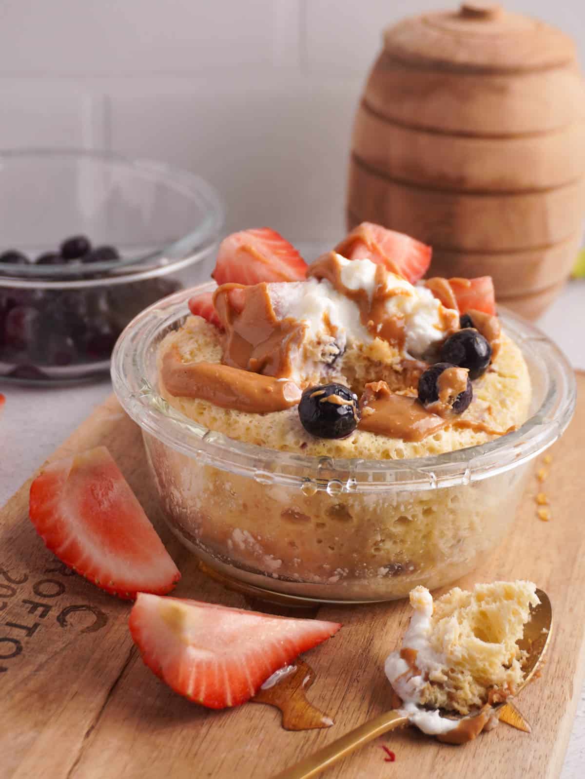 A protein pancake in a microwave safe bowl with berries, greek yogurt and honey drizzled on top.