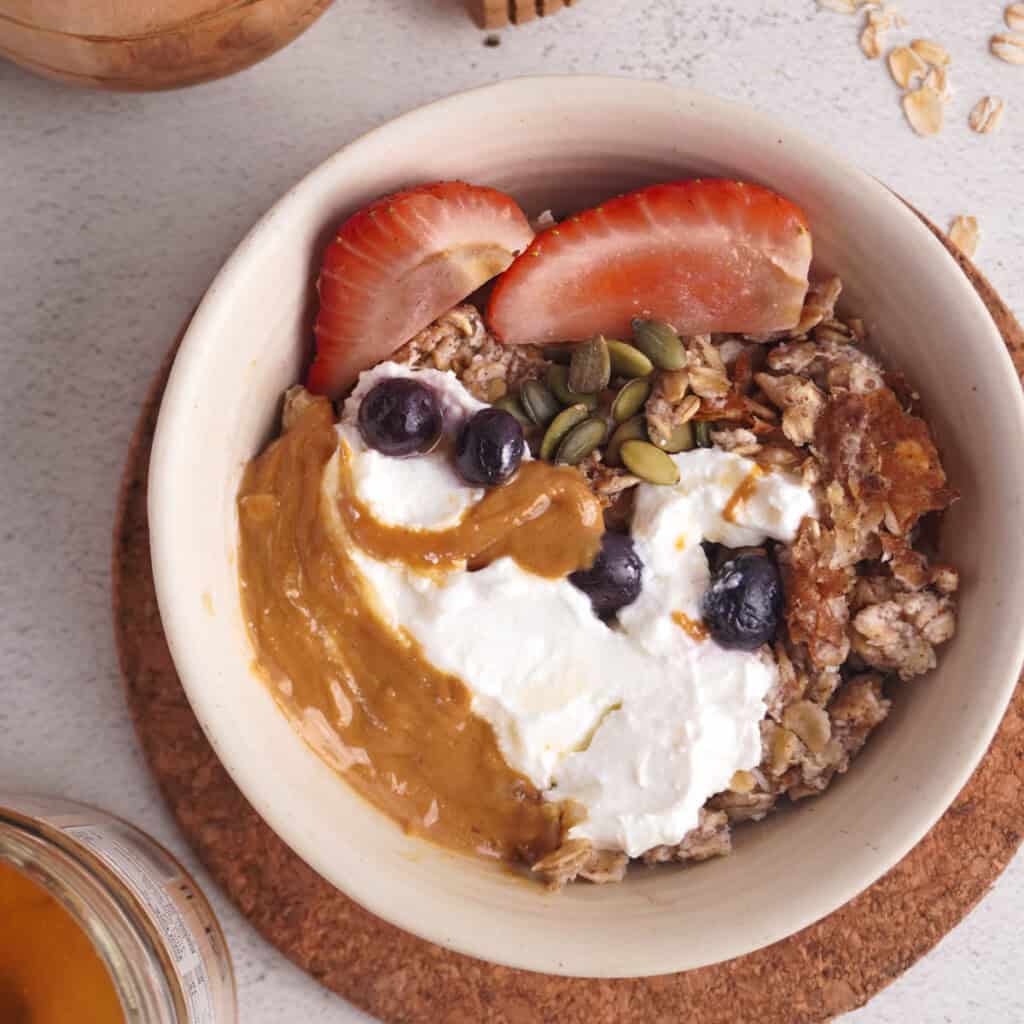 a bowl of scrambled oats with berries yogurt and peanut butter on top