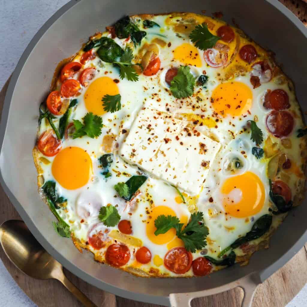 A skillet with baked eggs and feta cheese fresh out of the oven.