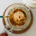 Peanut butter caramel sauce in a spoon over a mason jar.