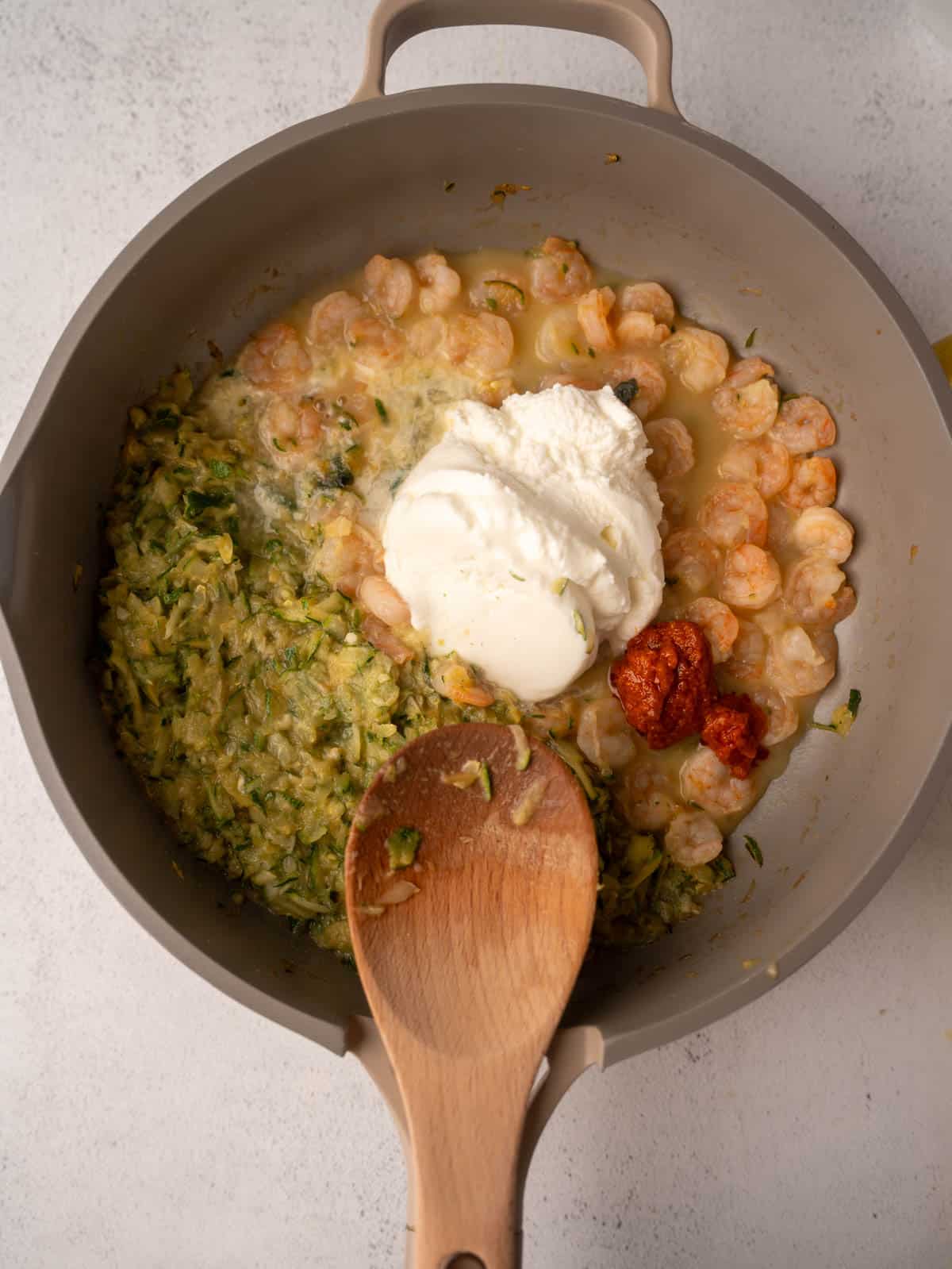 The next step is combining the creamy sauce and spaghetti for the Pesto Ricotta Pasta recipe. Ricotta cheese and pesto are added directly into the skillet with the cooked shrimp and zucchini are stirred together.