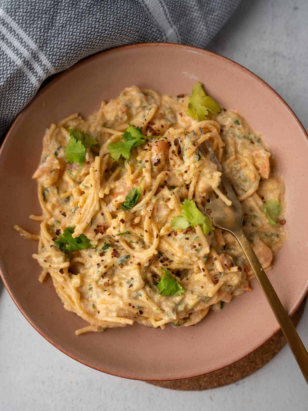 The finished Easy Pesto Ricotta Pasta with Shrimp recipe, served in a modern pink bowl to highlight the creamy texture of the sauce and the fresh herb garnish.