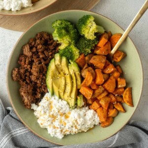 Sweet potato and ground beef bowl with broccoli, avocado, and cottage cheese that is plated nicely.