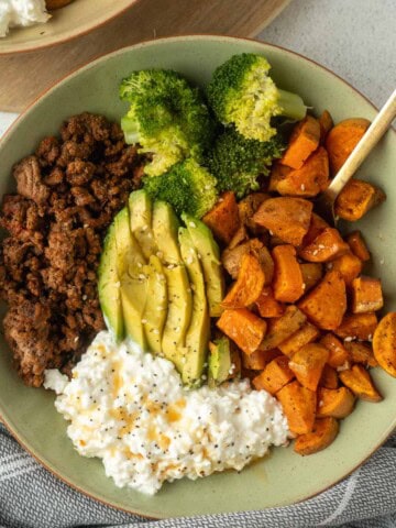 Sweet potato and ground beef bowl with broccoli, avocado, and cottage cheese that is plated nicely.