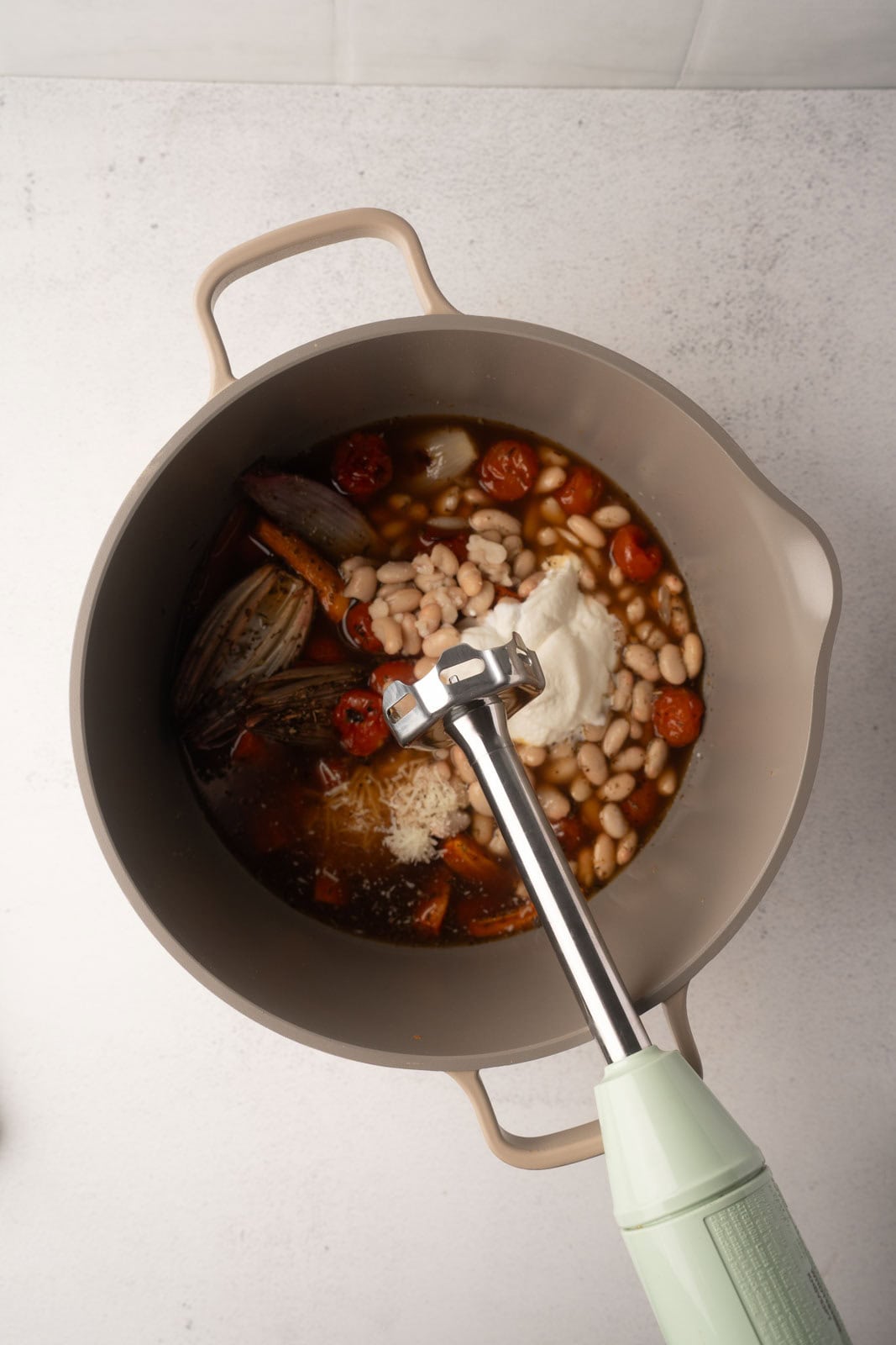 An immersion blender actively purées a creamy soup directly in the pot, showcasing the final stage of the tomato carrot soup recipe.