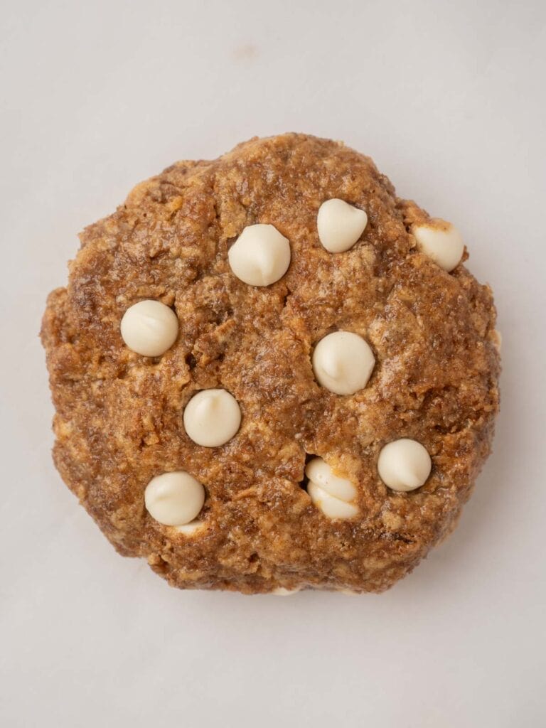 Close-up of a single baked Weetabix cake with melted white chocolate chips on top, sitting on parchment paper.
