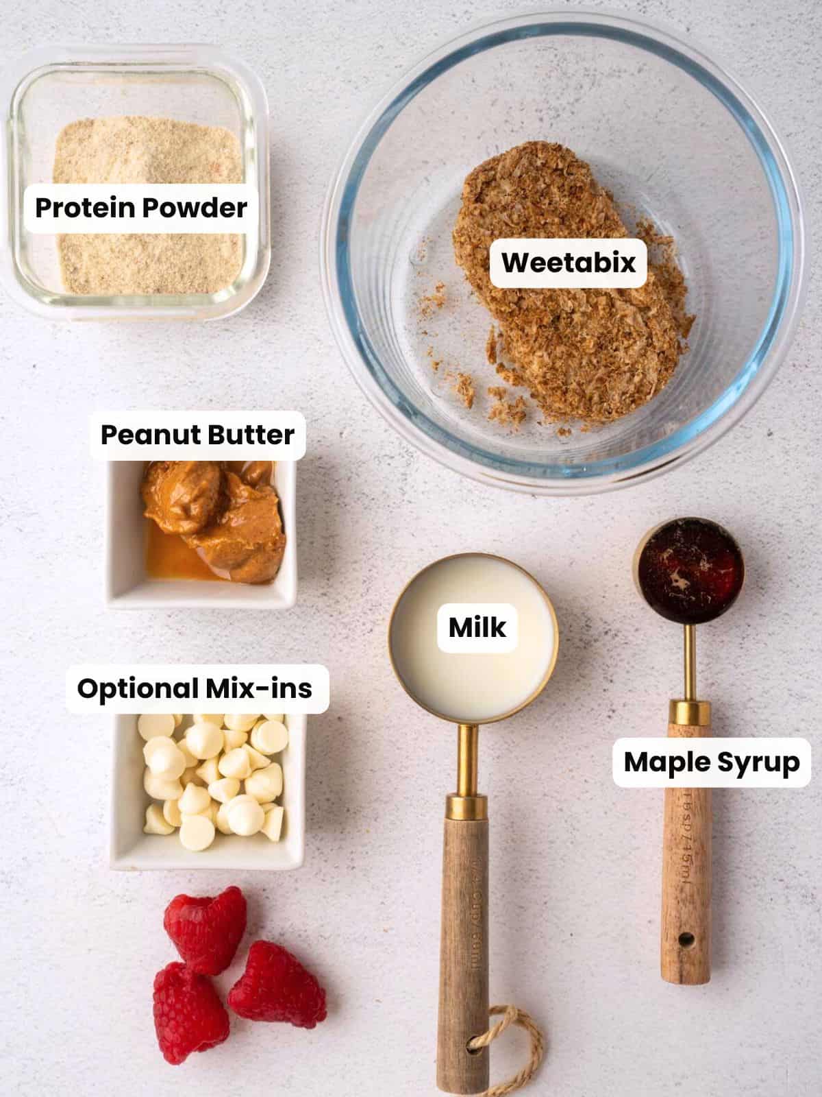 Overhead photo showing labeled ingredients for a high-protein Weetabix cookie on a light background.