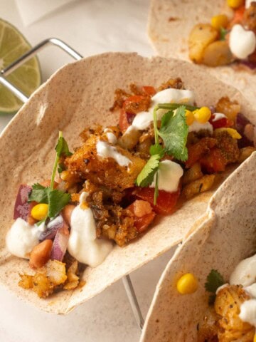Blackened cod fish tacos in whole wheat tortillas topped with corn, beans, cilantro, and a creamy lime sauce.