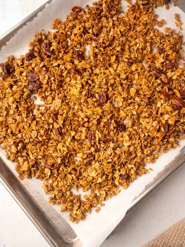 Freshly baked homemade granola cooling on a parchment-lined baking sheet