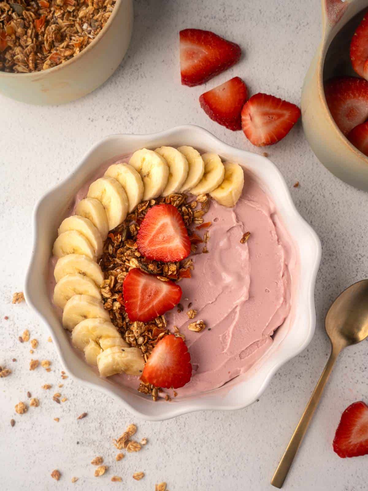 Strawberry banana Ninja Creami smoothie bowl topped with granola in a white bowl