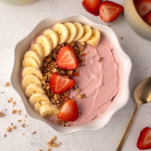 Strawberry banana Ninja Creami smoothie bowl topped with granola in a white bowl