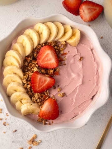 Strawberry banana Ninja Creami smoothie bowl topped with granola in a white bowl