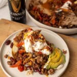 Guinness chili served over a baked potato with kidney beans, ground beef, avocado, sour cream, and shredded cheese.
