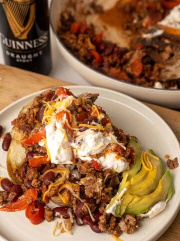 Guinness chili served over a baked potato with kidney beans, ground beef, avocado, sour cream, and shredded cheese.