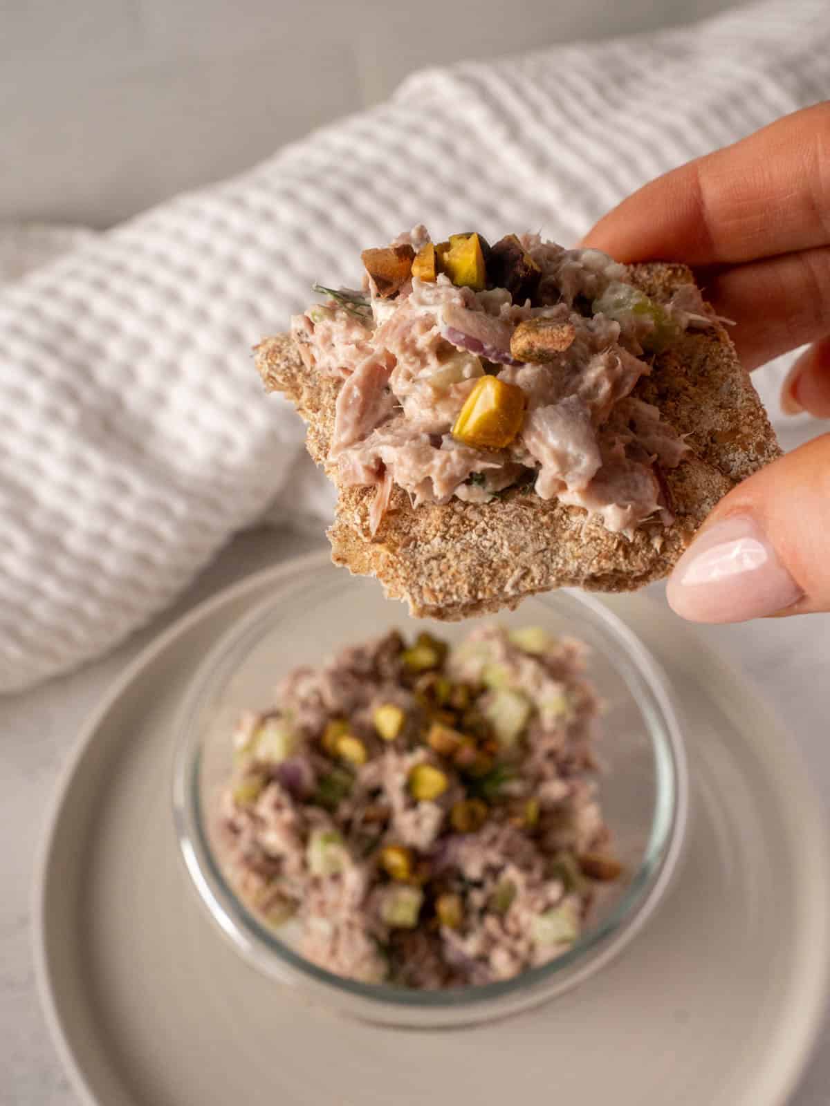 Healthy tuna salad recipe made with Greek yogurt, feta, pistachios, celery, red onion, and fresh dill, served in a glass bowl.