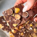 Frozen peanut butter banana bark topped with chocolate and crushed mini eggs, held in hand.
