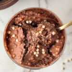 Chia seed protein pudding with a crunchy chocolate shell and crispy cereal pieces, with a spoon scooping through the center