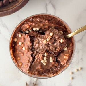 Chia seed protein pudding with a crunchy chocolate shell and crispy cereal pieces, with a spoon scooping through the center
