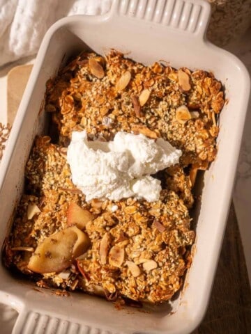 Healthy apple crumble with baked apples and oat topping, served in a white dish with a dollop of Greek yogurt and sprinkled nuts
