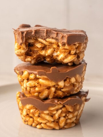 No bake chocolate peanut butter crispy cups with a bite showing crispy rice cereal texture and creamy chocolate topping