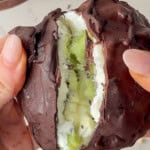 Close-up of a chocolate-coated frozen yogurt kiwi bite being pulled apart to reveal a creamy Greek yogurt filling and fresh kiwi slices inside