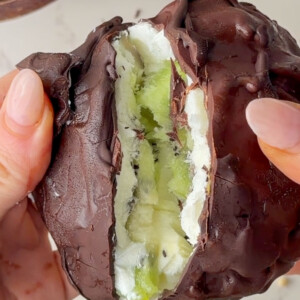 Close-up of a chocolate-coated frozen yogurt kiwi bite being pulled apart to reveal a creamy Greek yogurt filling and fresh kiwi slices inside
