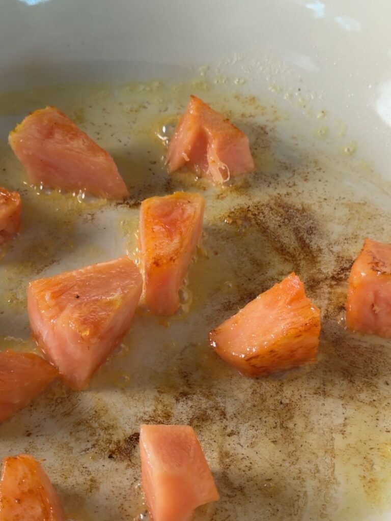 Pineapple chunks caramelizing in a skillet until golden brown around the edges.