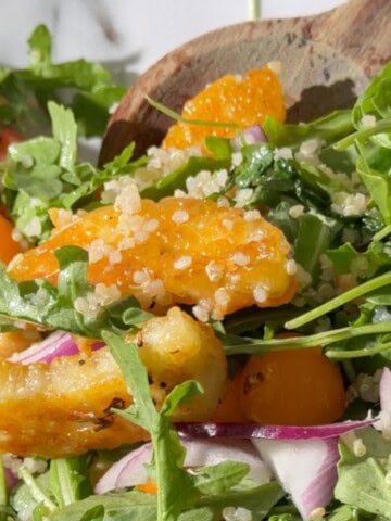 close up of a chickpea and halloumi salad with quinoa being picked up with wooden spoons