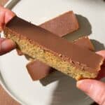 Close-up of a no-bake chocolate peanut butter hemp seed bar showing its fudgy hemp and oat base with a smooth chocolate topping.