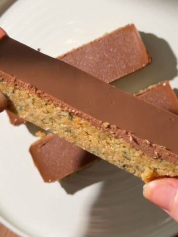 Close-up of a no-bake chocolate peanut butter hemp seed bar showing its fudgy hemp and oat base with a smooth chocolate topping.
