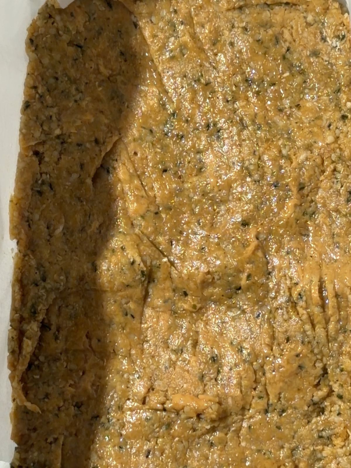 Hemp seed and peanut butter mixture pressed into a parchment-lined loaf pan.