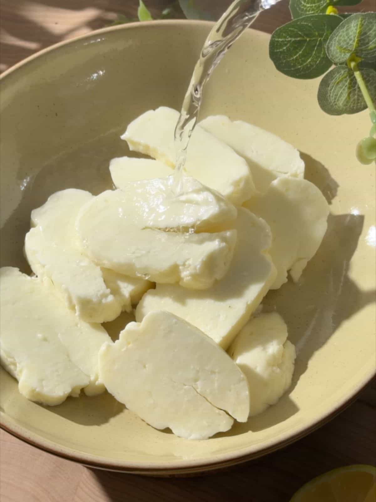 Sliced halloumi soaking in water before making hot honey halloumi.