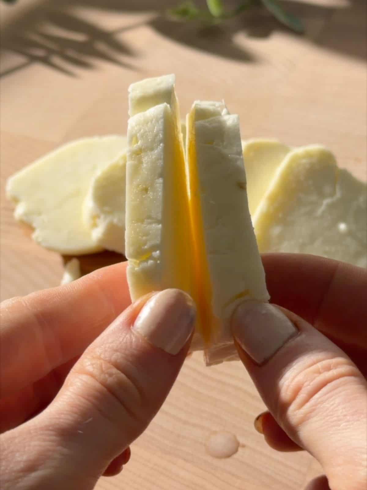 Fresh halloumi being sliced into thick pieces before pan-frying.