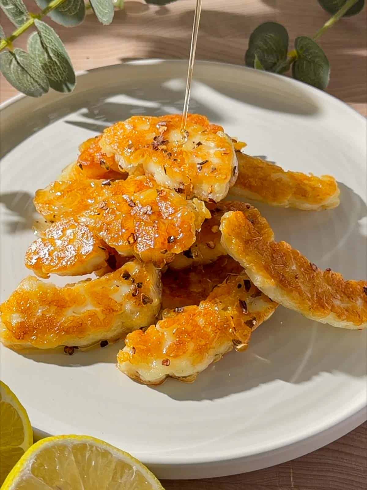 Hot honey halloumi with golden pan-fried halloumi pieces drizzled with honey and chilli flakes on a plate.