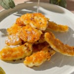 Hot honey halloumi with golden pan-fried halloumi pieces drizzled with honey and chilli flakes on a plate.