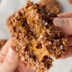 Salted caramel chocolate quinoa crisps broken in half to show the chewy caramel center and flaky sea salt topping.