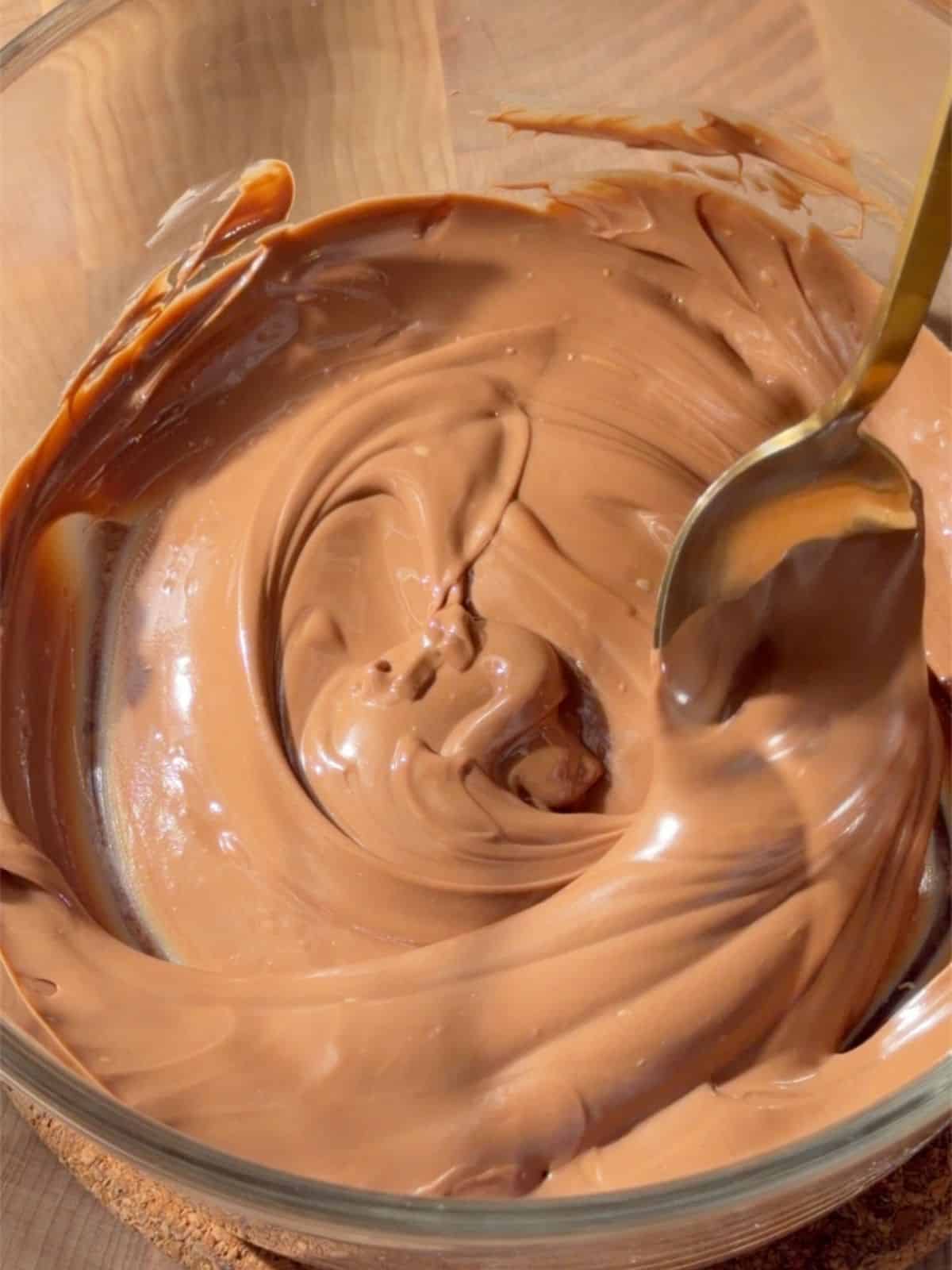 Melted chocolate in a glass bowl ready to mix with puffed quinoa.