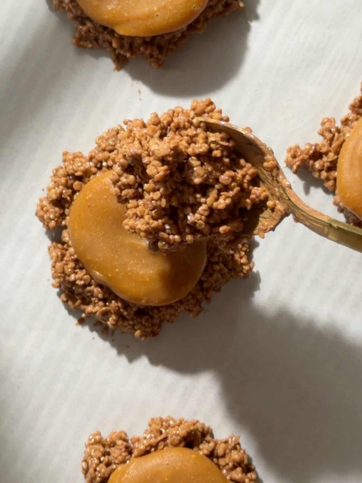 Frozen peanut butter caramel disc placed on top of a chocolate quinoa crisp base before adding the final layer.