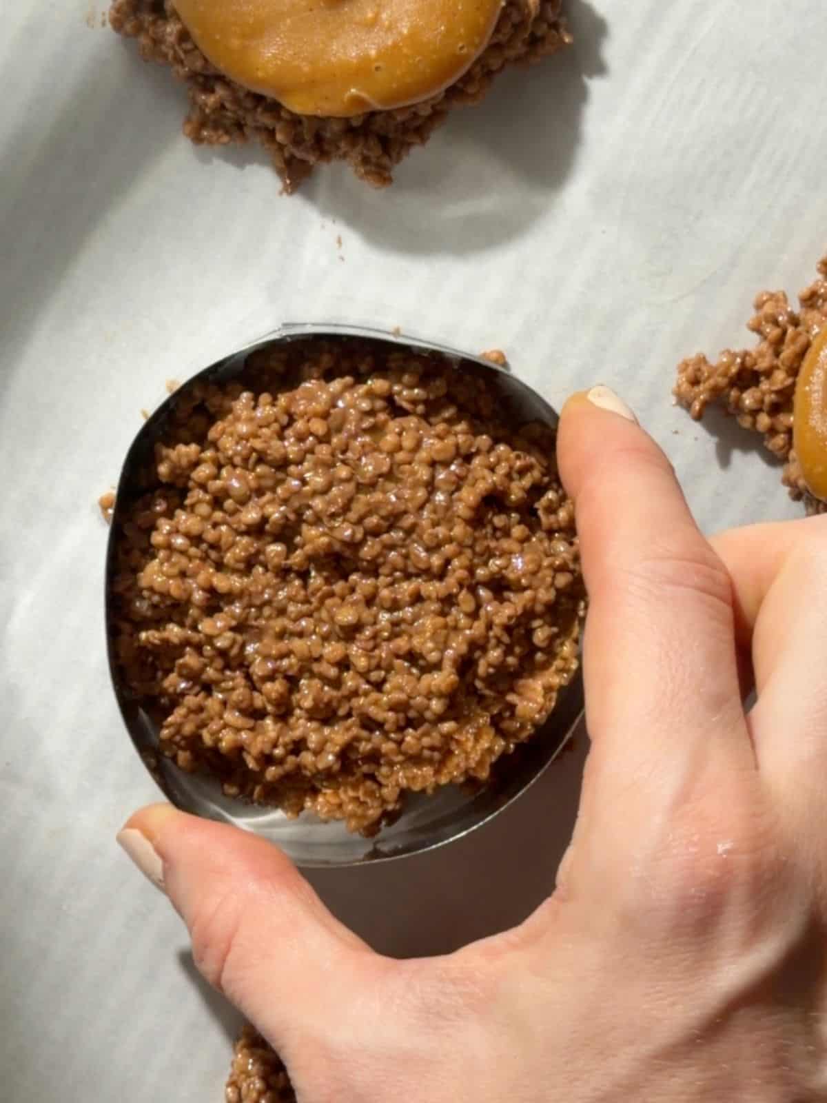 Using a circular cookie cutter to shape the chocolate quinoa mixture into neat rounds.