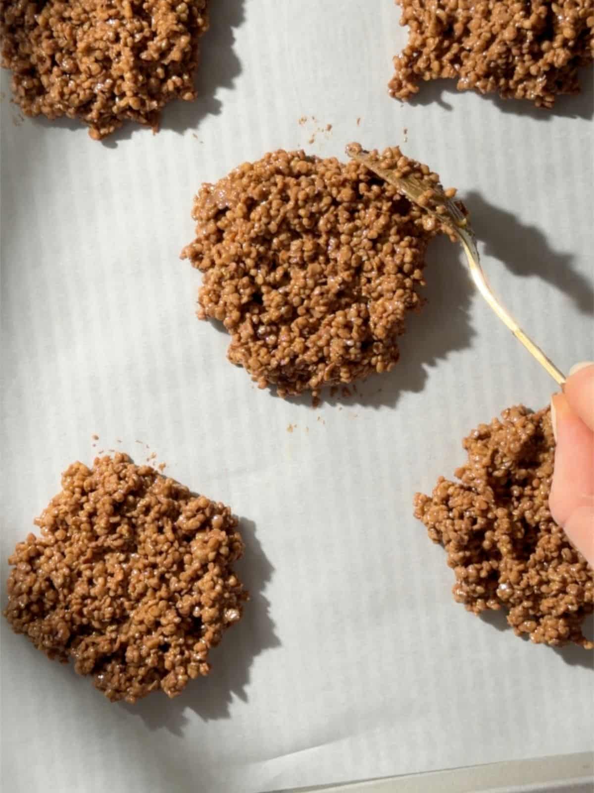 Chocolate quinoa mixture being spooned onto a parchment-lined tray to make salted caramel chocolate quinoa crisps.