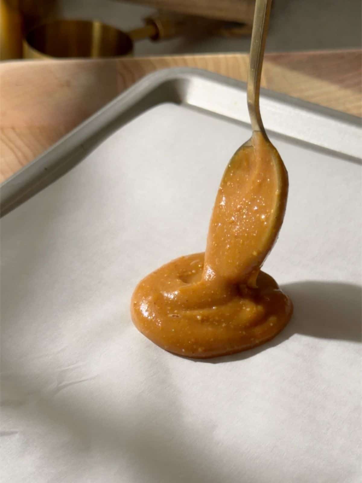Peanut butter caramel being spooned onto parchment paper to make the caramel centers