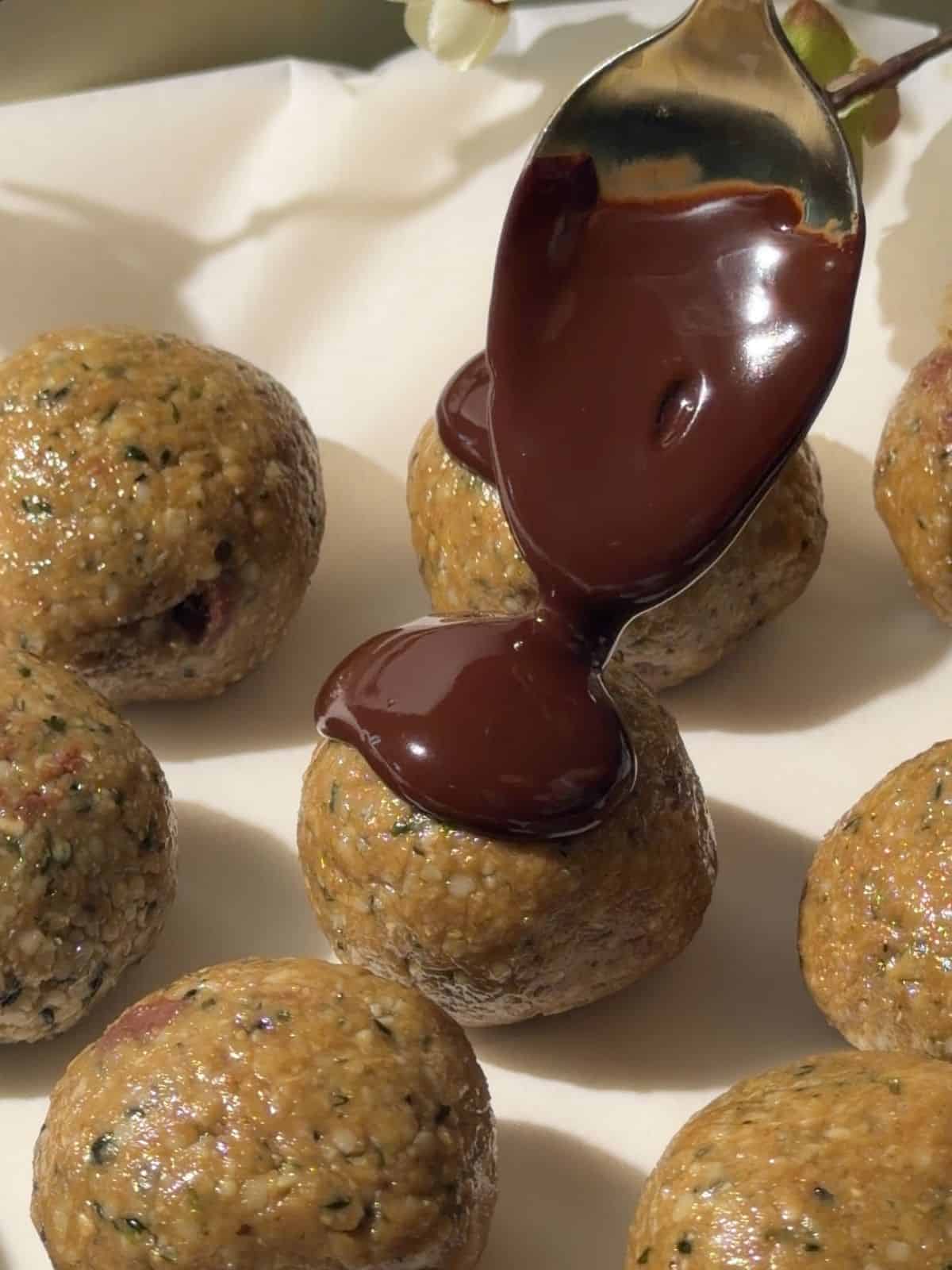 Drizzling melted chocolate over homemade nut free protein balls