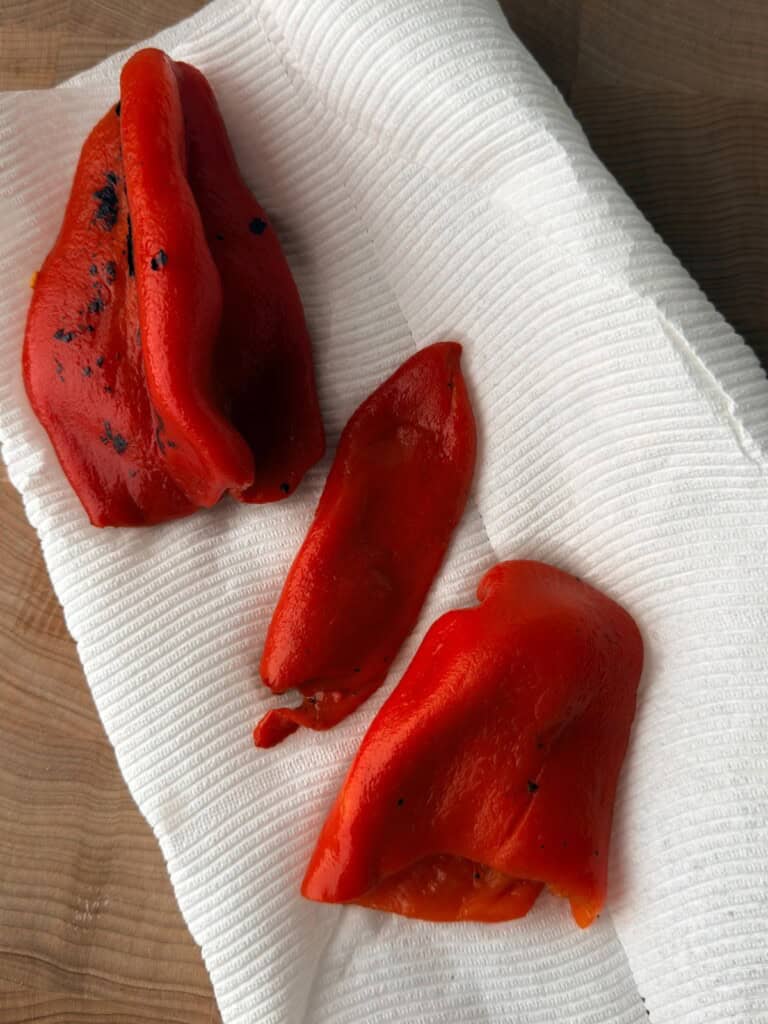 Roasted red peppers draining on paper towels before being used in a muhammara recipe.