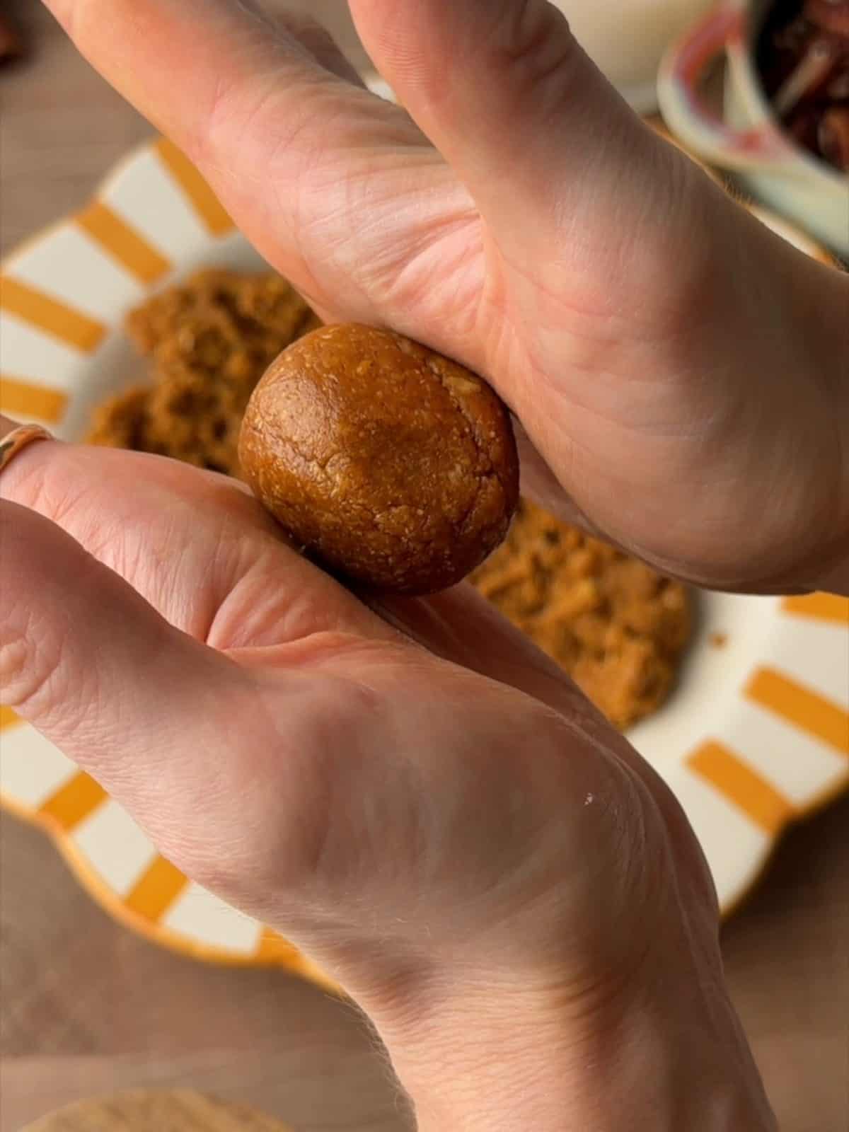 Pumpkin protein ball mixture being rolled into balls by hand.