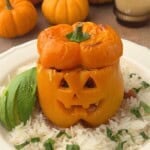 Jack o lantern stuffed pepper filled with ground turkey, topped with melted cheese, and served over rice with sliced avocado and fresh cilantro.